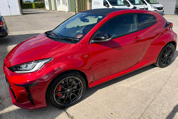 red sporty hatchback car with black wheels parked on pavement stylish design high performance 1 driving experience